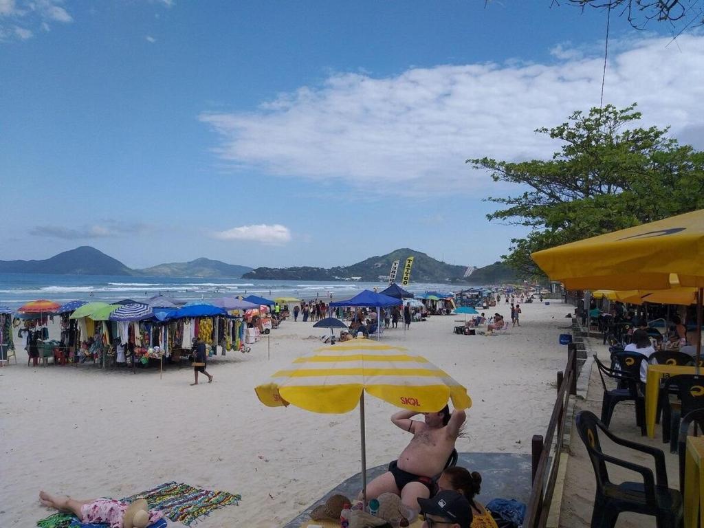 a group of people sitting under an umbrella on the beach at Cantinho do sossego na praia grande Ubatuba in Ubatuba