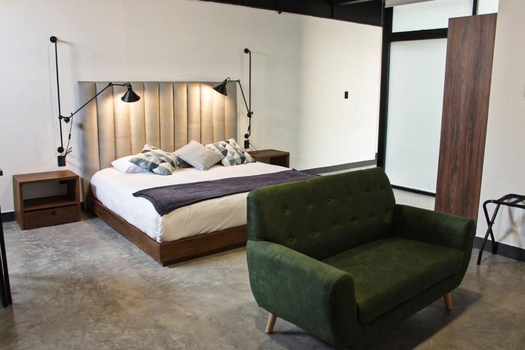 a bedroom with a bed and a green chair at Loft cobalto en excelente ubicación! in San Luis Potosí