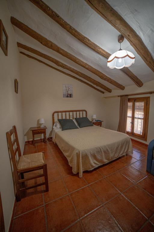 1 dormitorio con cama, silla y techo en Pension Las Cuevas de Cañart, en Las Cuevas de Cañart
