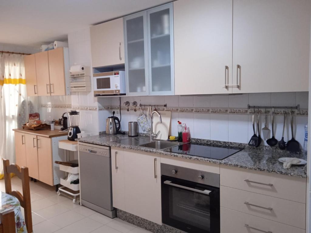 a kitchen with white cabinets and a stove top oven at ALQUILO Habitación doble baño privado in Torremolinos