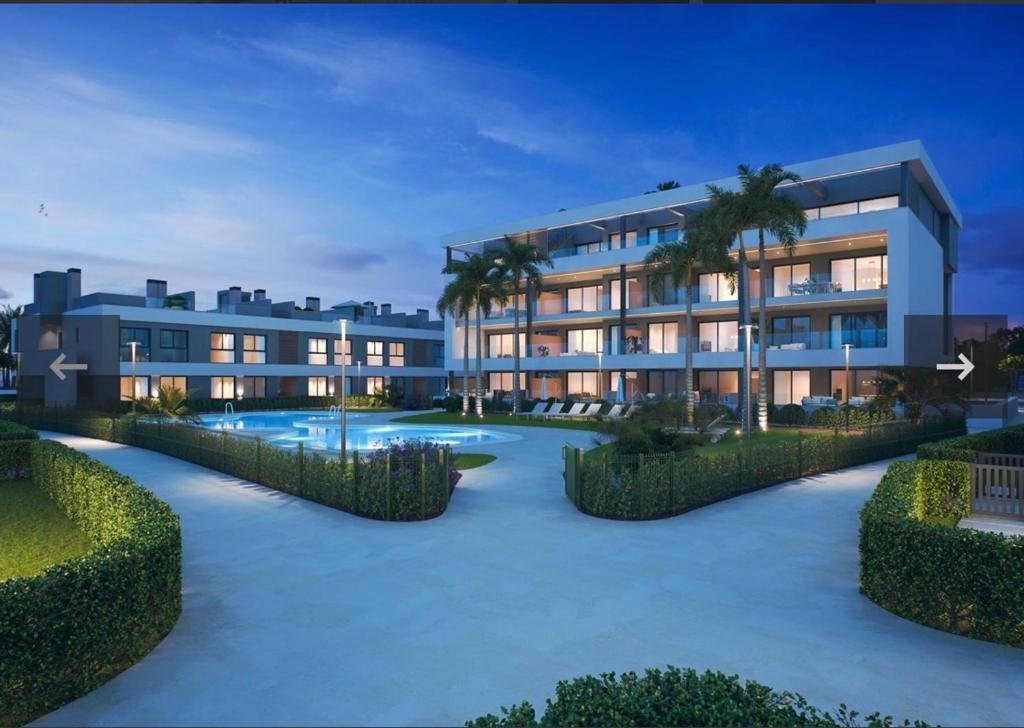 洛斯阿爾卡薩雷斯的住宿－Jacuzzi Penthouse appartement Santa Rosalia Lake & Life Resort Murcia Golf，一座建筑,前面有游泳池和棕榈树