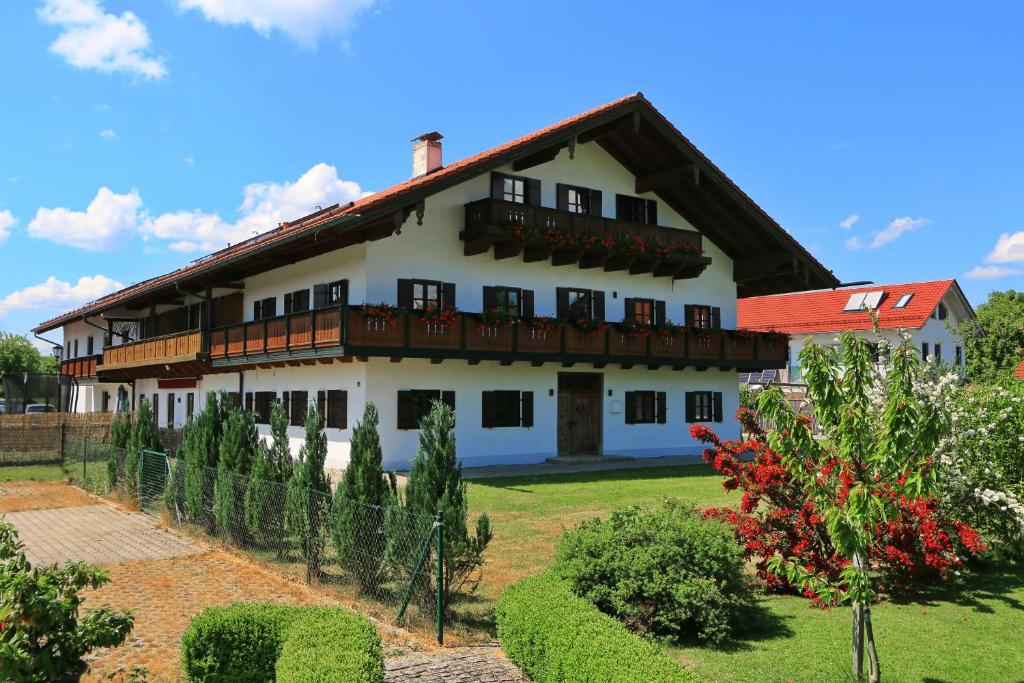 uma grande casa branca com um telhado vermelho em Gutshof Alpenblick am Simssee - über den man spricht em Stephanskirchen
