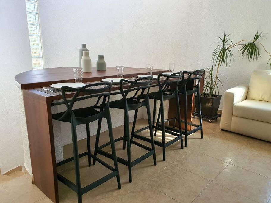 a wooden table with black chairs and a table and a couch at Hermoso departamento con excelente ubicación in San Luis Potosí