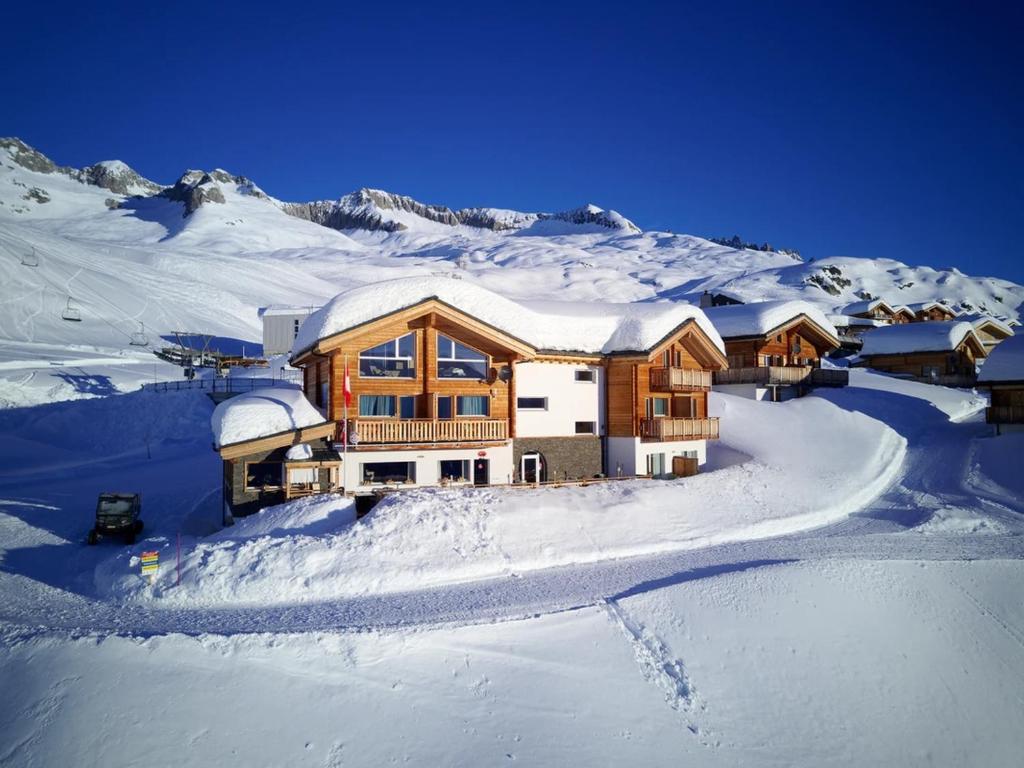 une maison dans la neige avec des montagnes enneigées dans l'établissement Hotel Harmony Tigilou Belalp, à Belalp