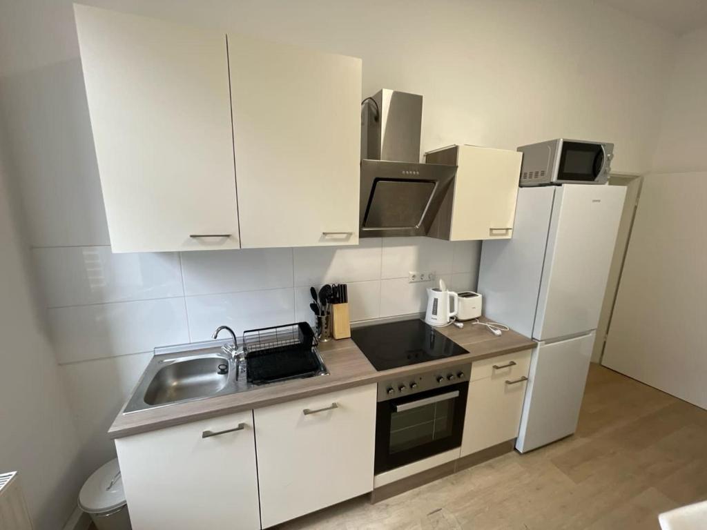 a kitchen with white cabinets and a sink and a refrigerator at L8 Street-Worms in Worms