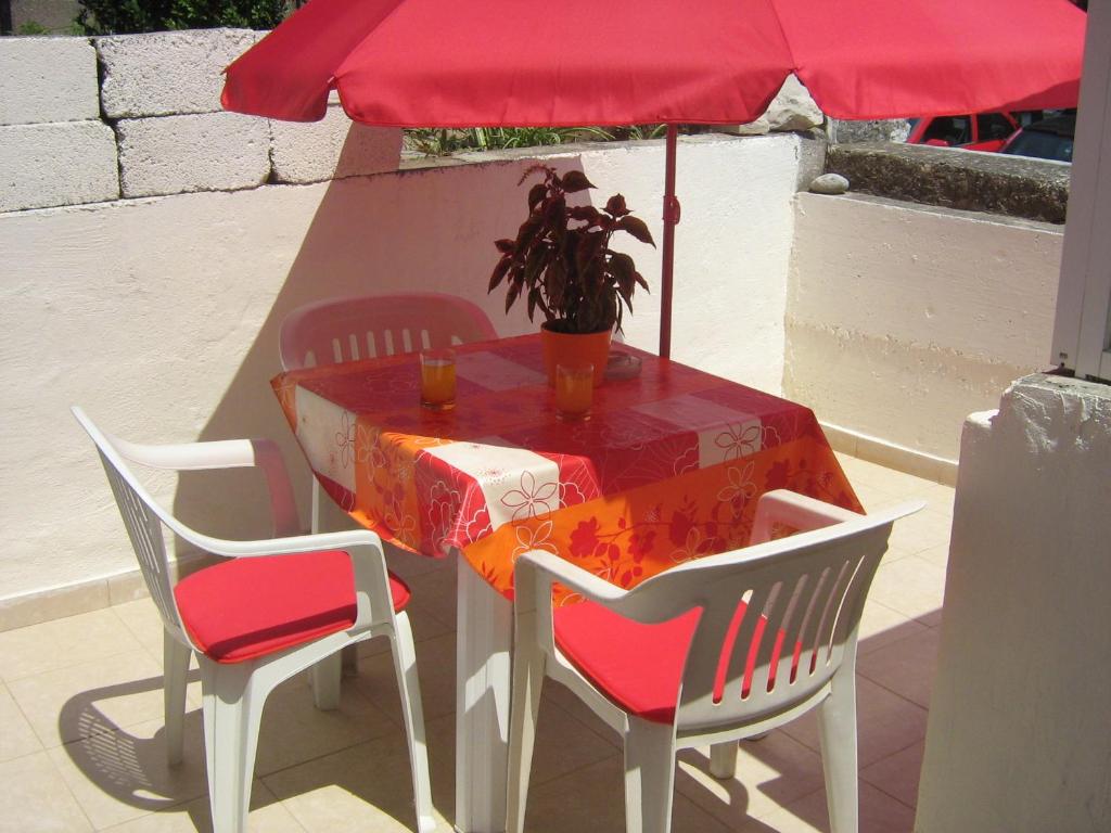 una mesa con una sombrilla rosa y una mesa con sillas en Linda Apartment, en Korčula