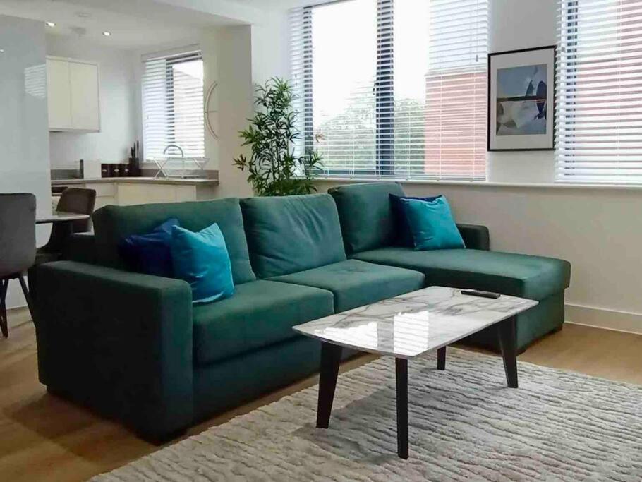 a green couch in a living room with a table at Luxury 2 Bed 2 Bath Flat Near Old Trafford in Manchester