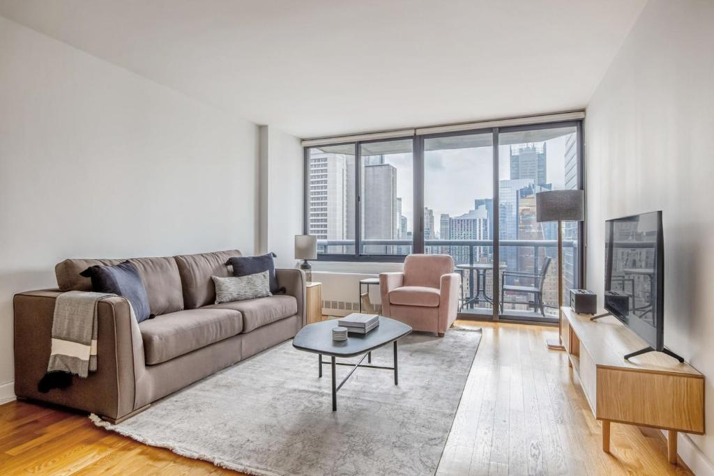 een woonkamer met een bank en een tafel bij Midtown 2br w elevator wd nr entertainment NYC-1227 in New York