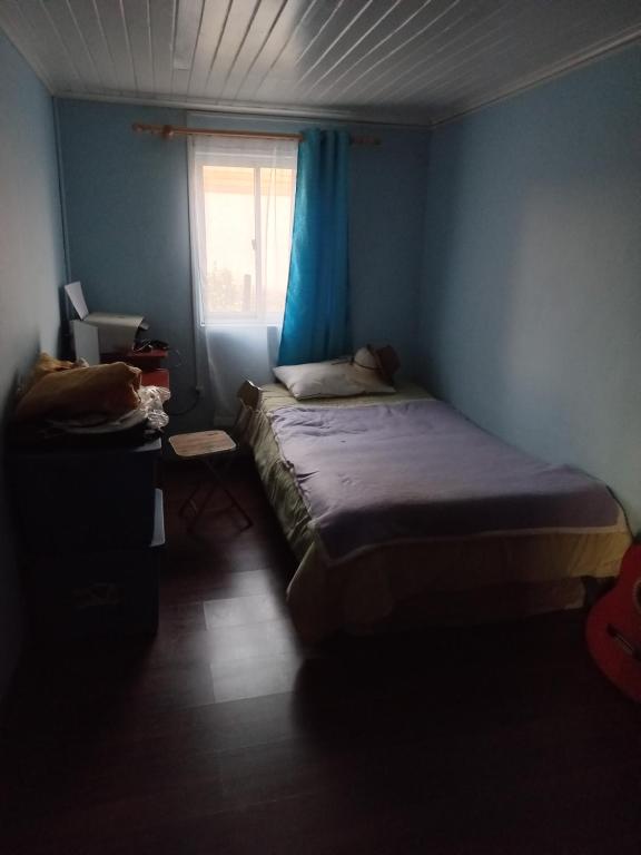 um pequeno quarto com uma cama e uma janela em Roomtraiguen em Lehuelán