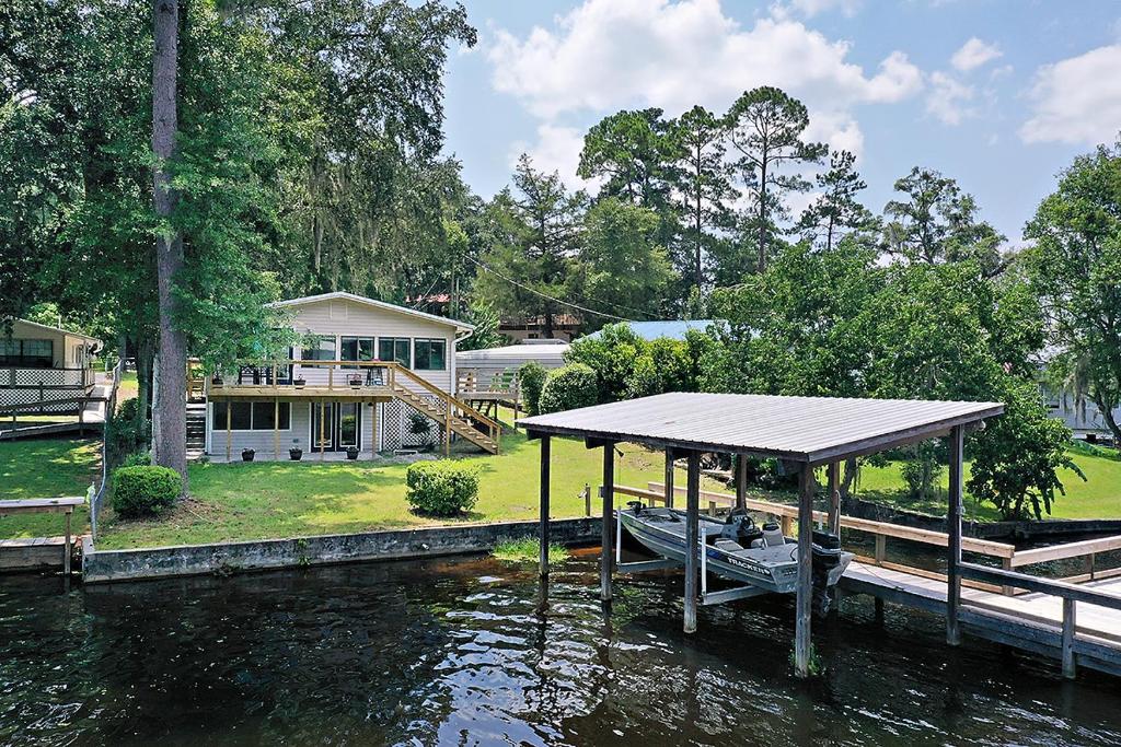 a house on the water with a dock and a boat at Modern Retreat Lake House @Lake Talquin in Tallahassee