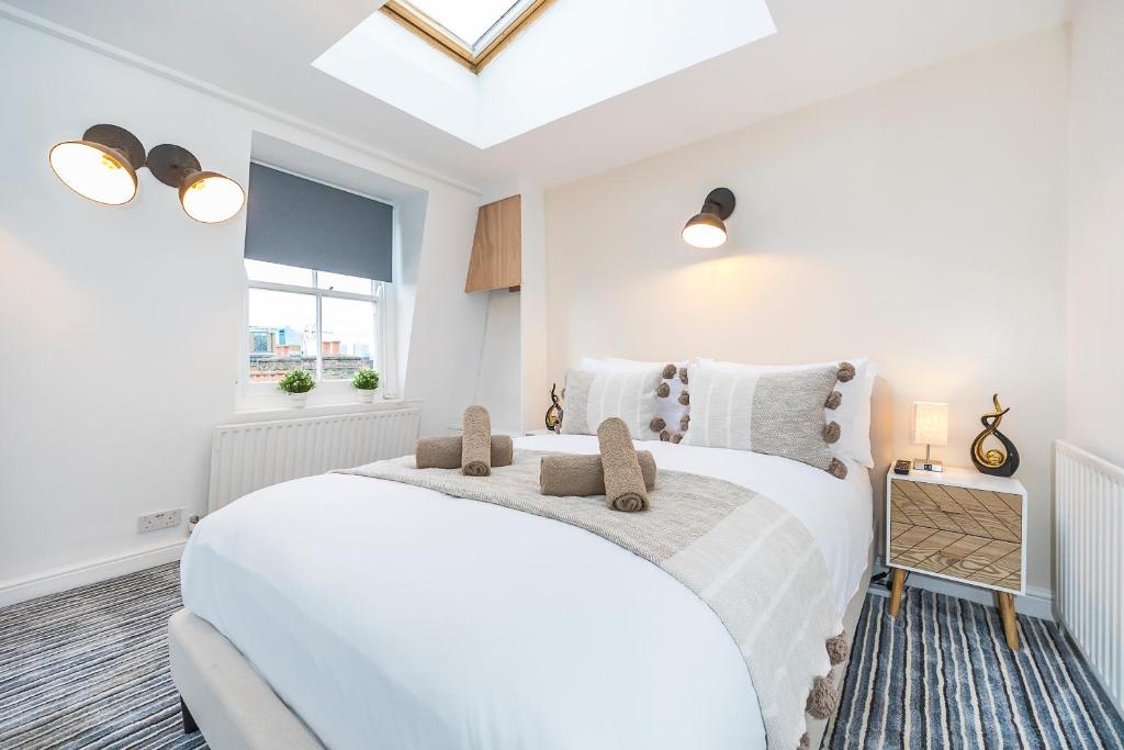 a white bedroom with a white bed and a window at Verv Brick Lane in London