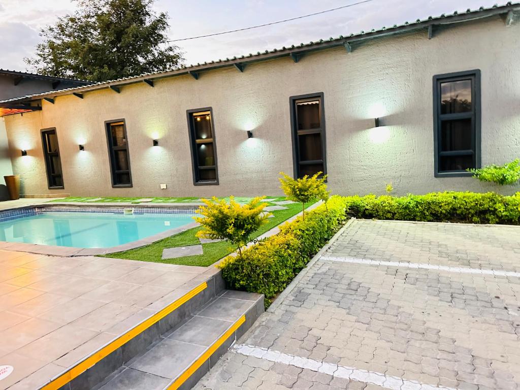 a house with a swimming pool next to a building at Signature Boutique Guesthouse in Maun