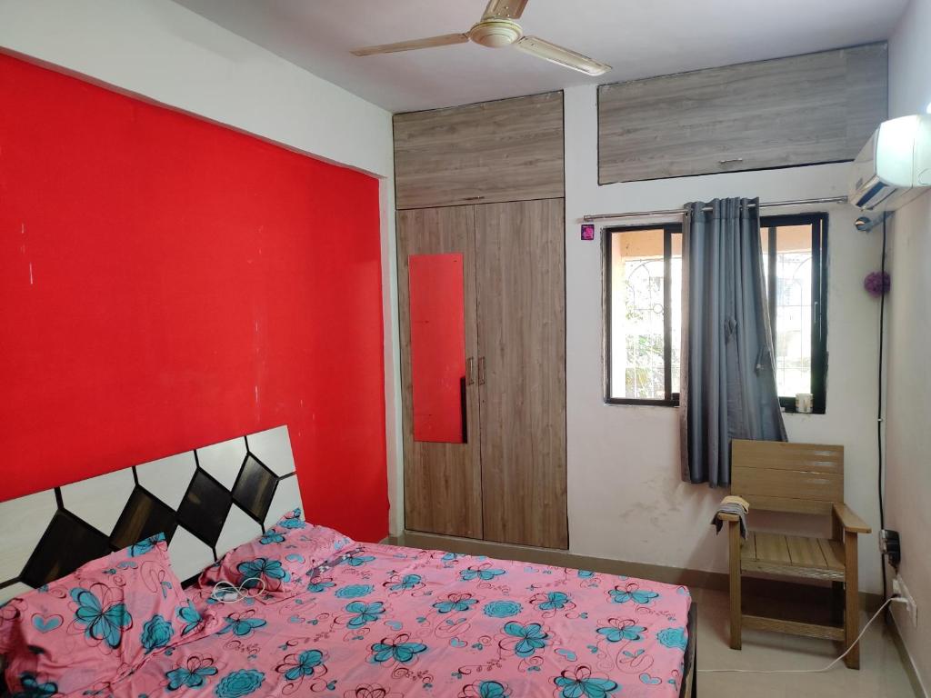 a bedroom with a pink bed with a red wall at GharApna Hostel in Mumbai