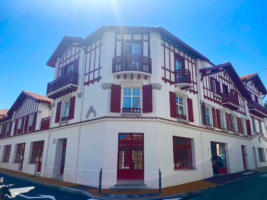 een groot wit gebouw met rode deuren en ramen bij Best Western Kemaris in Biarritz