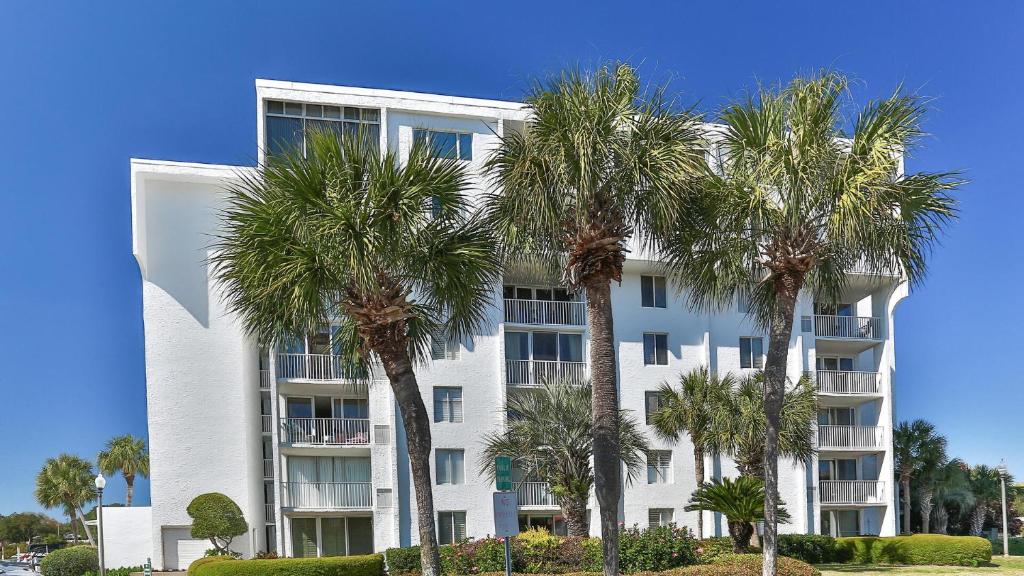 a white building with palm trees in front of it at Dolphin Point 404B - 2BR on Holiday with Views of Harbor in Destin