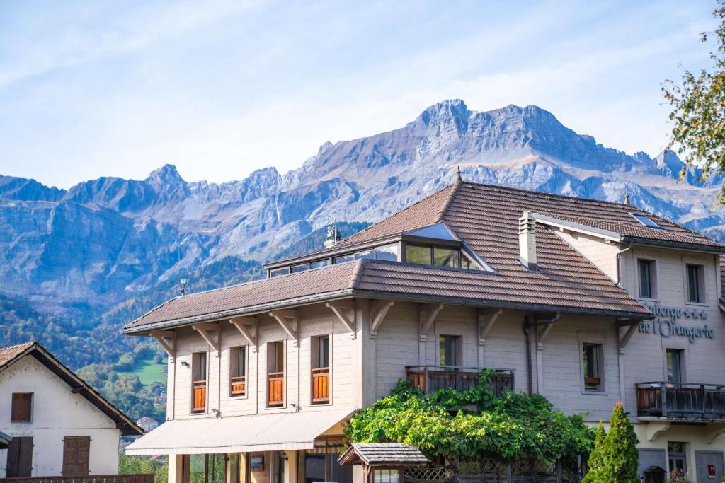 Une grande maison blanche avec une montagne en arrière-plan dans l'établissement Auberge de l'Orangerie - Sure Hotel Collection by Best Western, à Sallanches