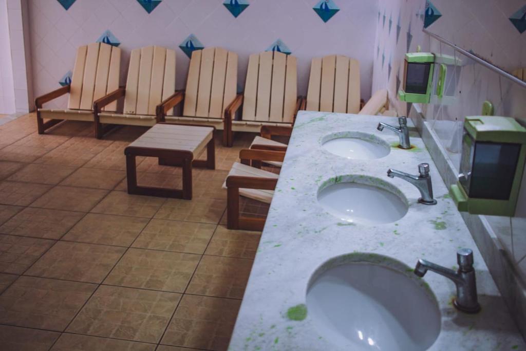 Baño público con 2 lavabos y una fila de sillas en Ilha1 - Condominio Marinas Do Canal en Cabo Frío