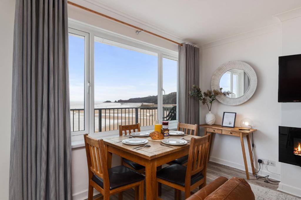 Un comedor con una mesa y un gran ventanal. en Sea Urchins - Sea Front Apartment with Views, en Saundersfoot