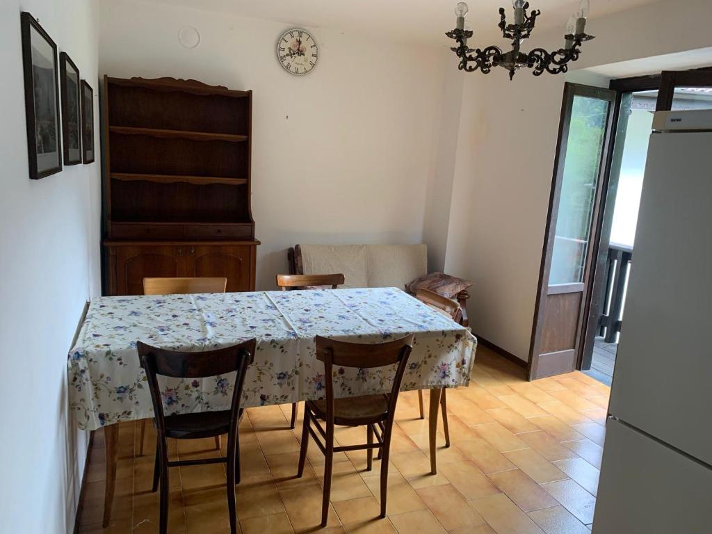 a dining room with a table and chairs and a clock at Appartamento a Bagolino (BS) in Bagolino