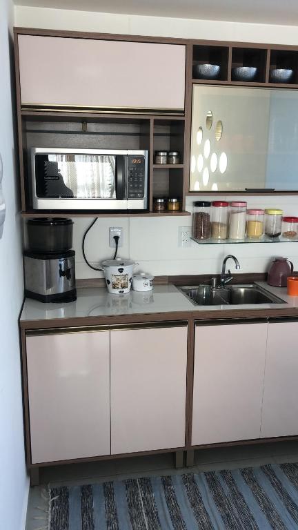 a kitchen with a sink and a microwave at Apartamento encantandor-perto centro e shopping in Poços de Caldas