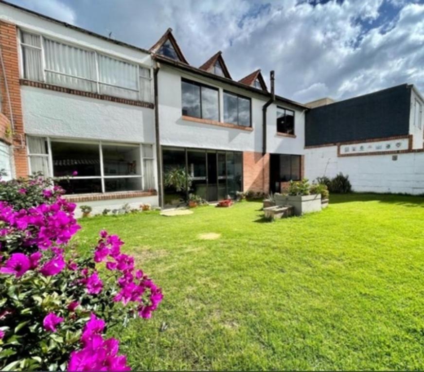 a large house with a yard with purple flowers at Casa Tipo Chalet especial Grupos grandes in Bogotá