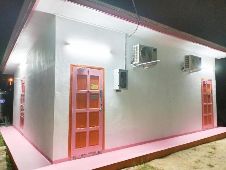 a white building with a red door and a fan at Chalet Roomstay Mini Private Pool,Penginapan Teratak KandaMus in Kuala Terengganu