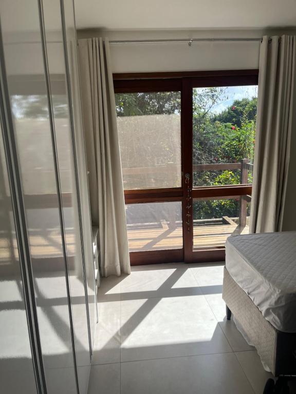 a bedroom with a window with a view of a yard at Suites Amma Noronha in Fernando de Noronha
