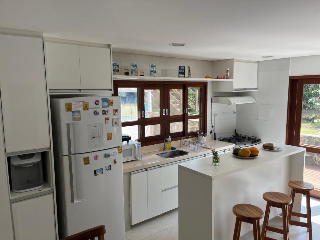 a kitchen with white cabinets and a white refrigerator at Suites Amma Noronha in Fernando de Noronha