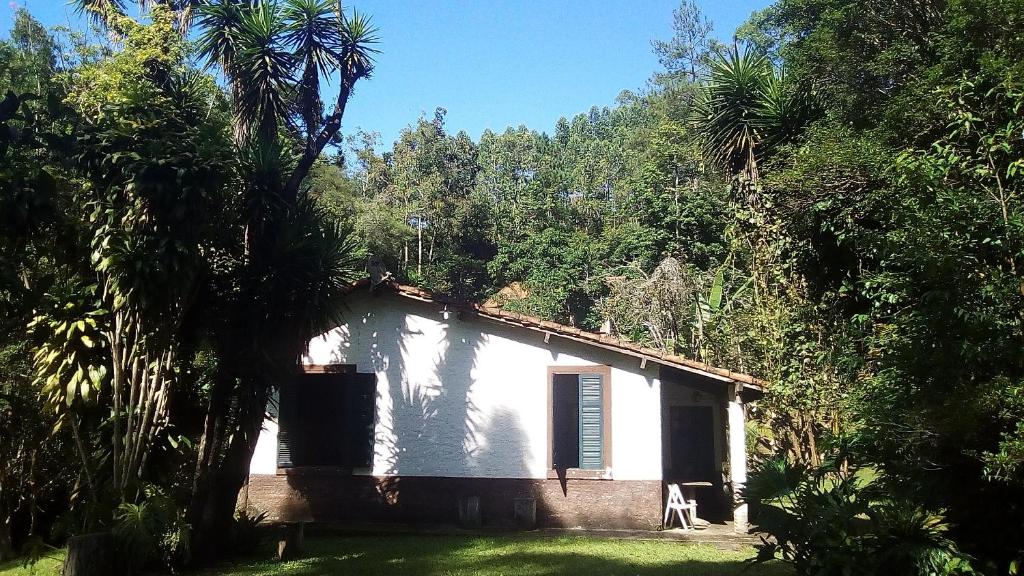 een klein wit huis midden tussen de bomen bij Casa hospedagem rural em São Roque in Itapevy