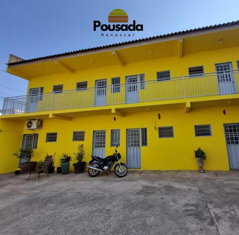 a motorcycle parked in front of a yellow building at Pousada Renascer in Cuiabá