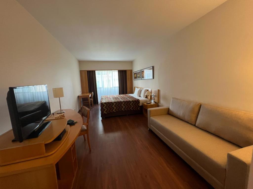 Hotel Alphaville Apto 703 في باروري: غرفة معيشة مع أريكة وسرير