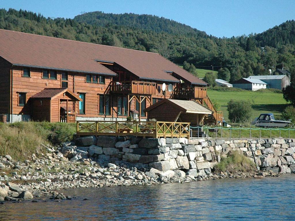 a large wooden house next to a body of water at Six-Bedroom Holiday home in Eidsvåg in Eidsvåg