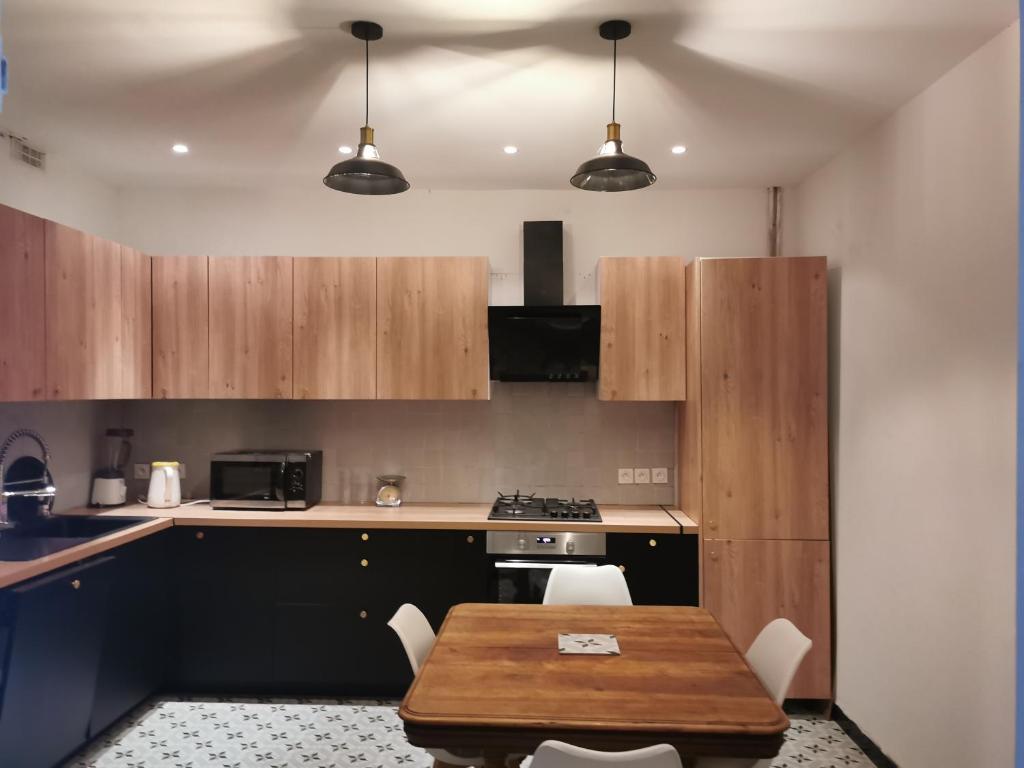 - une cuisine avec une table en bois, des chaises et une cuisinière dans l'établissement Magnifique maison années 30 proche des remparts, à Avignon