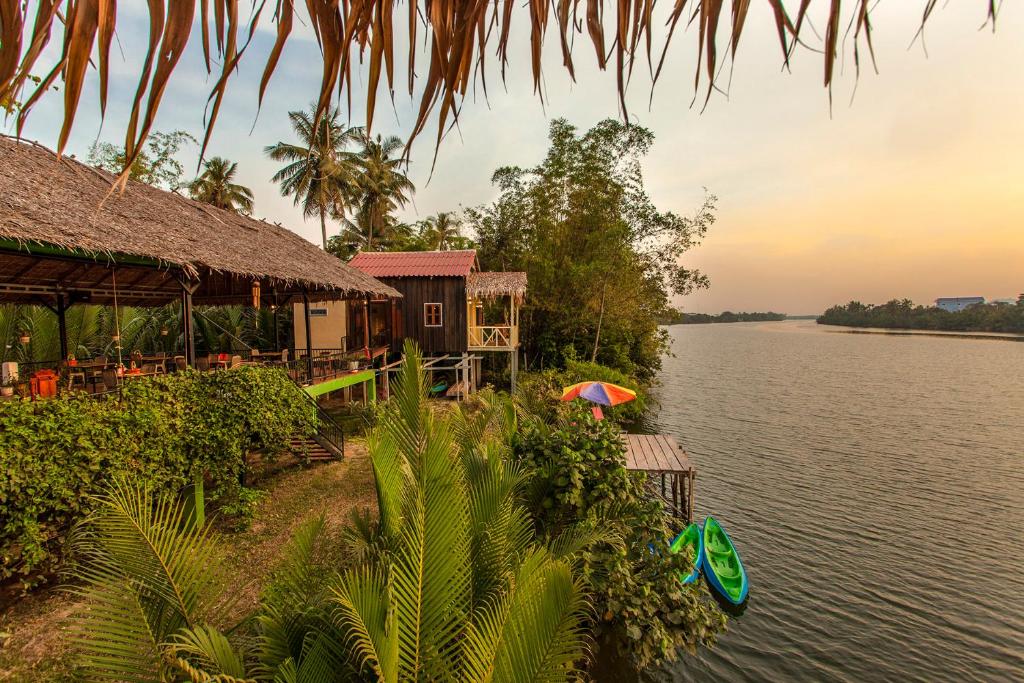 a house with an umbrella next to a body of water at Green Mango Bungalows in Kampot