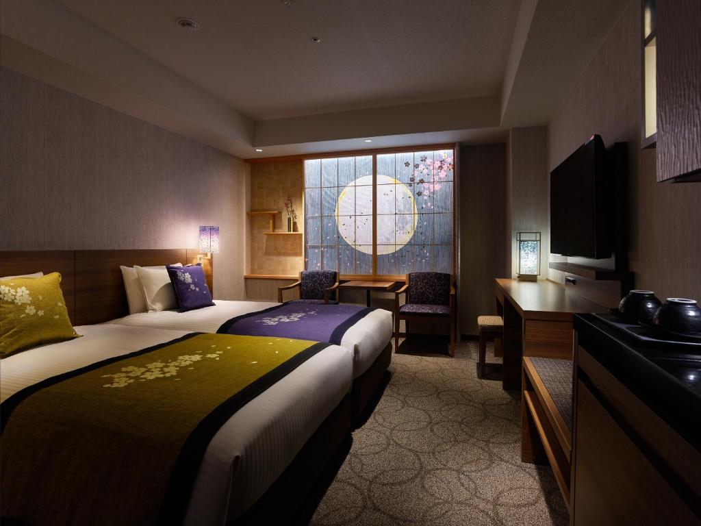 a hotel room with two beds and a desk and a window at Mitsui Garden Hotel Kyoto Station in Kyoto