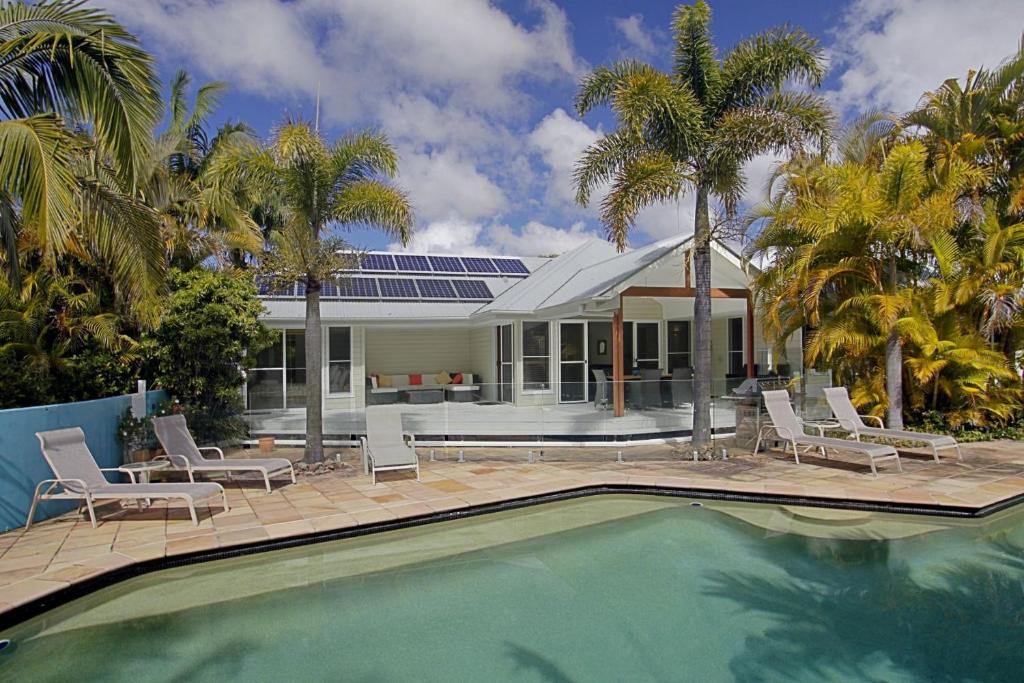 a house with a swimming pool and palm trees at A Perfect Stay - Abode at Byron in Ewingsdale