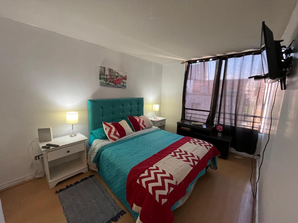 a bedroom with a bed with a green headboard and a television at Apartment Relocation San Isidro in Santiago