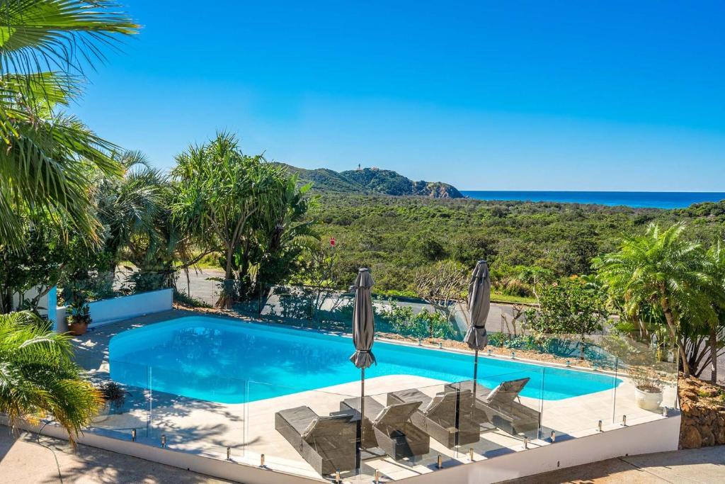 a swimming pool with chairs and a view of the ocean at A Perfect Stay - Byron Pacific Vista in Byron Bay