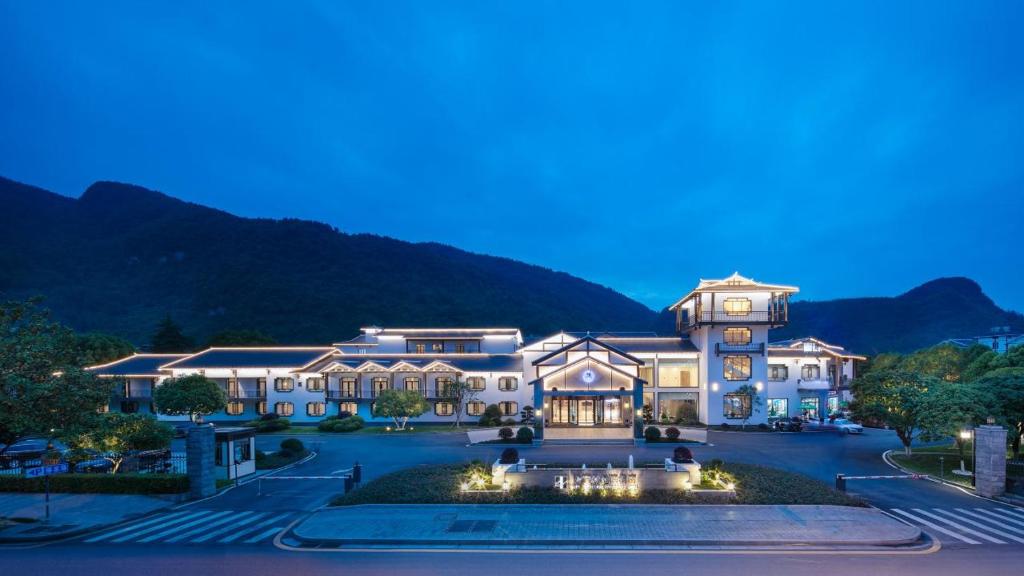 un grande palazzo con montagne sullo sfondo di NATIONAL SCENIC SPOT SUNSHINE RESORT HOTEL a Zhangjiajie