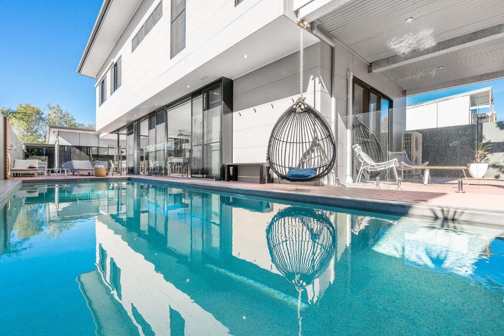 una piscina con columpio y una casa en A Perfect Stay - Catalinas, en Byron Bay