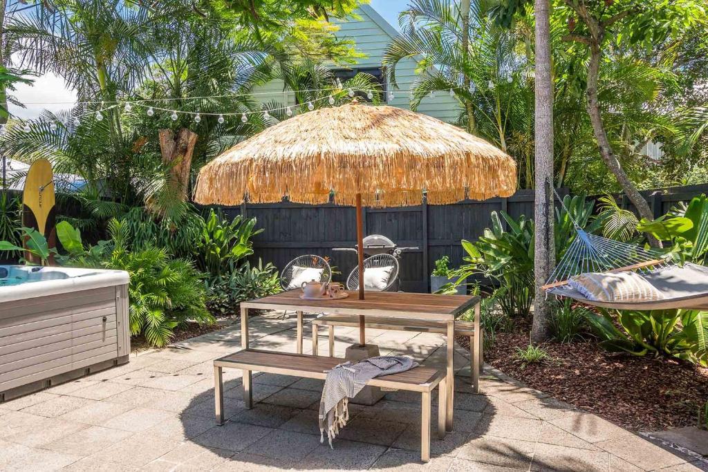 a table and two chairs and a straw umbrella at A Perfect Stay - Gidgets House and Studio in Byron Bay