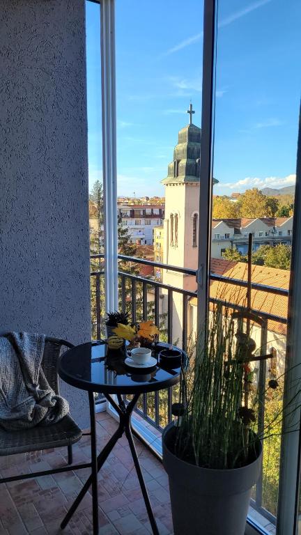 a table on a balcony with a view of a church at Apartman Riva in Kraljevo