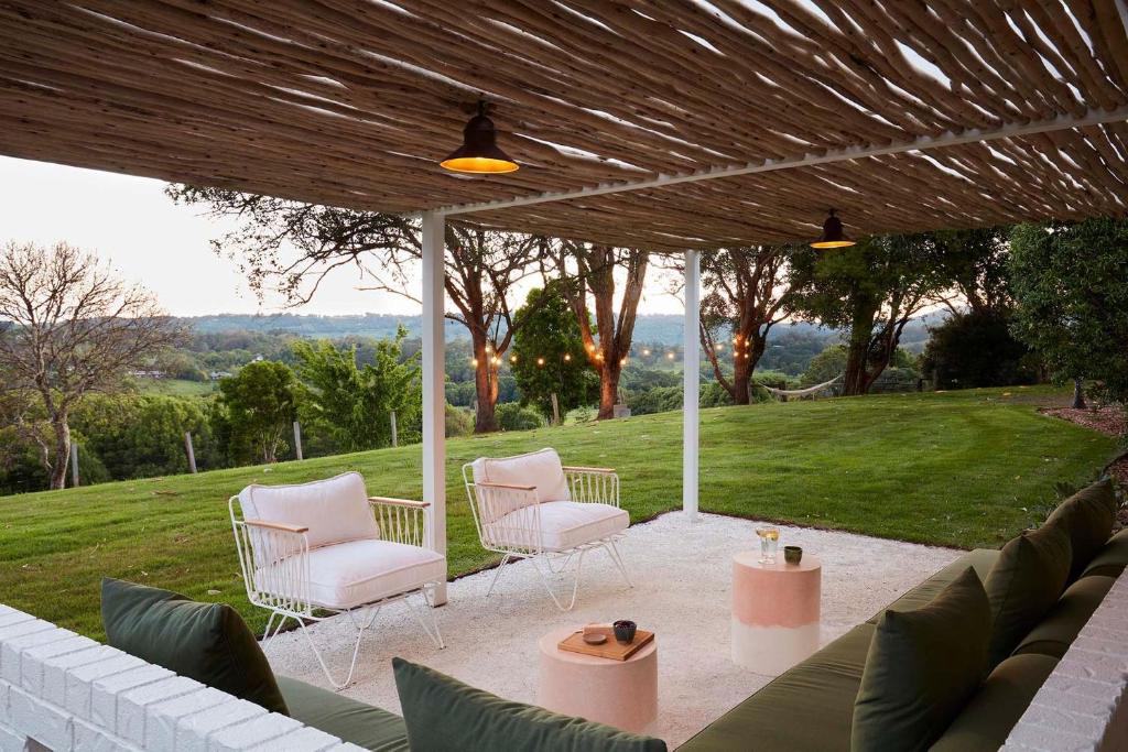 acovered patio with two chairs and a table with a view at Hidden Byron - designer hinterland oasis with pool, fireplace and firepit in Myocum