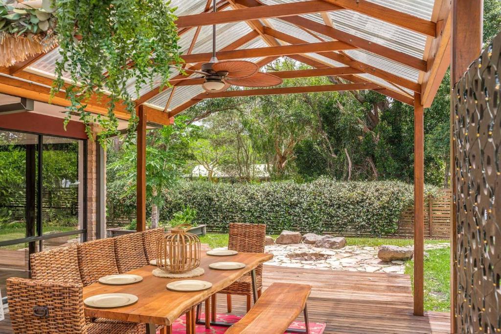 A Perfect Stay - Julian Rocks House في خليج بايرون: فناء مع طاولة وكراسي خشبية ومظلة