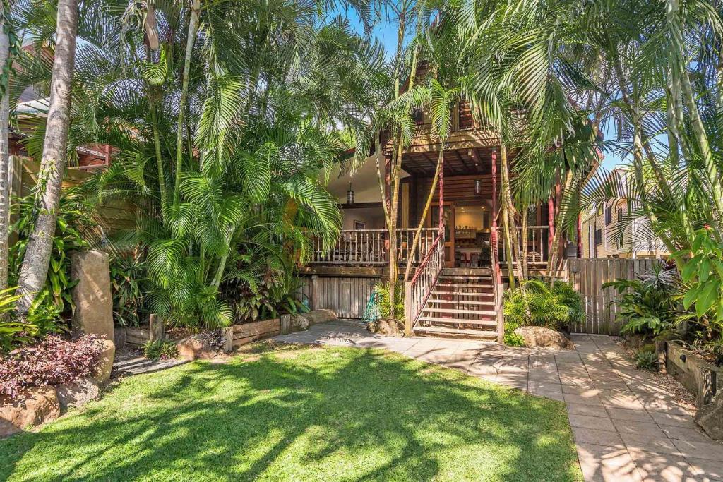 a house with palm trees in front of a yard at A Perfect Stay - Longhouse in Byron Bay