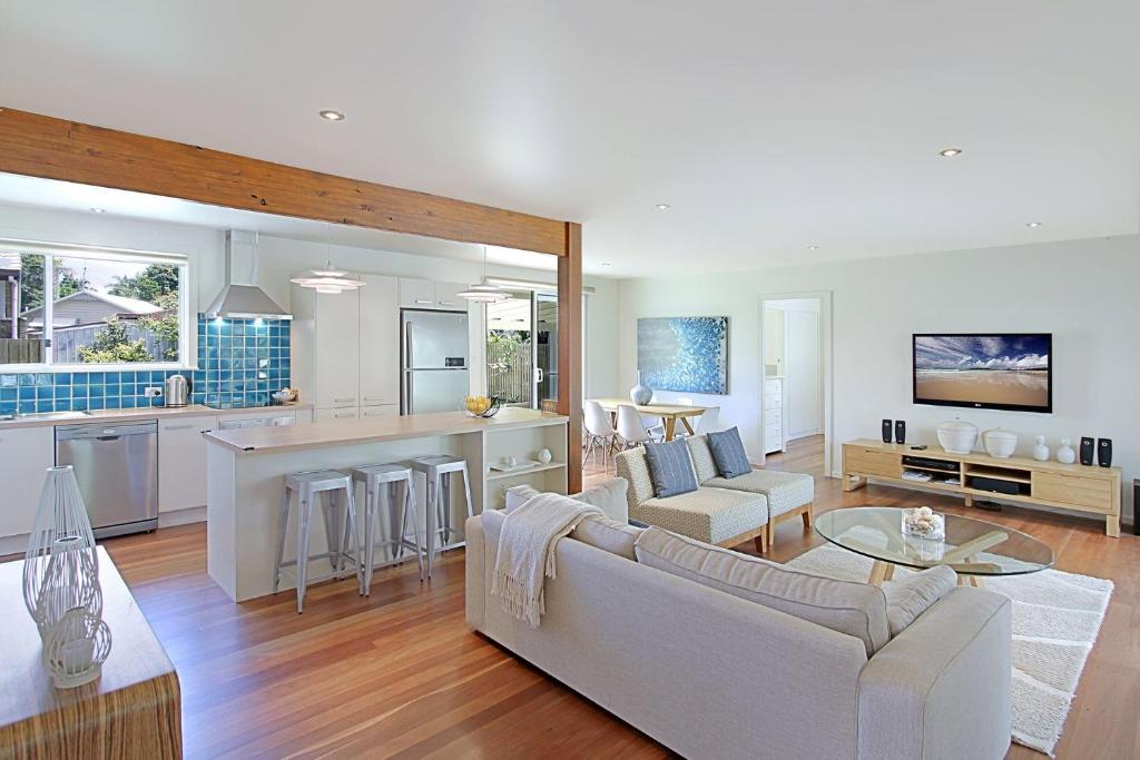 a living room and kitchen with a couch and a table at Mi Casa - stylish beach house near town & surf in Byron Bay