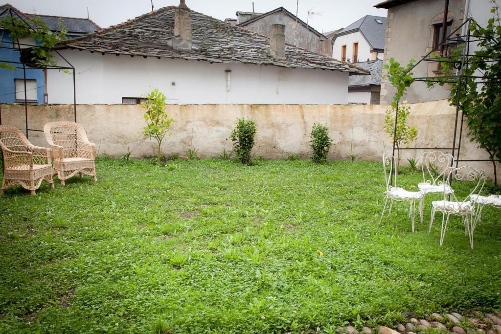 einen Garten mit Stühlen, Tischen und einer Wand in der Unterkunft Casona Puerto de Vega in Puerto de Vega