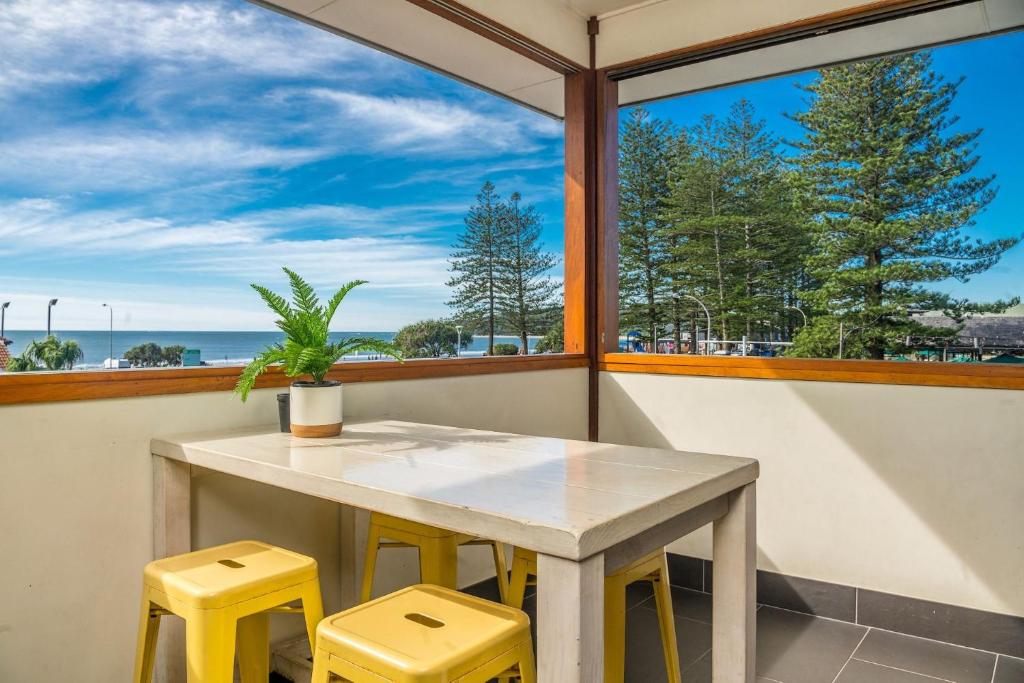 a table and two yellow stools in front of a window at Quiksilver Apartments The Pass - steps from beach in Byron Bay