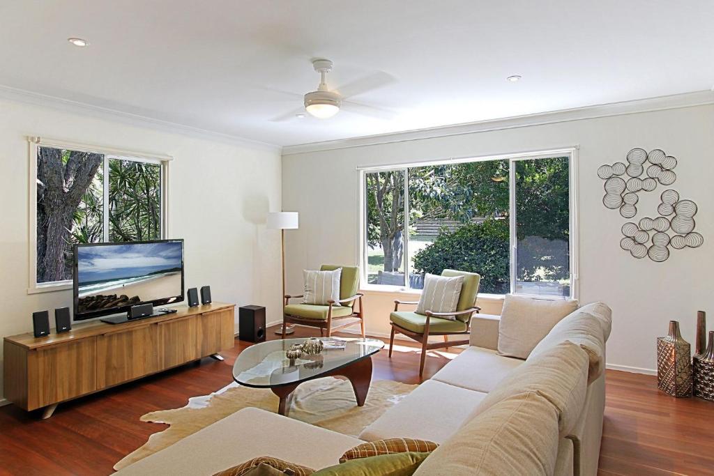 sala de estar con sofá y TV de pantalla plana en A Perfect Stay - Su Casa, en Byron Bay