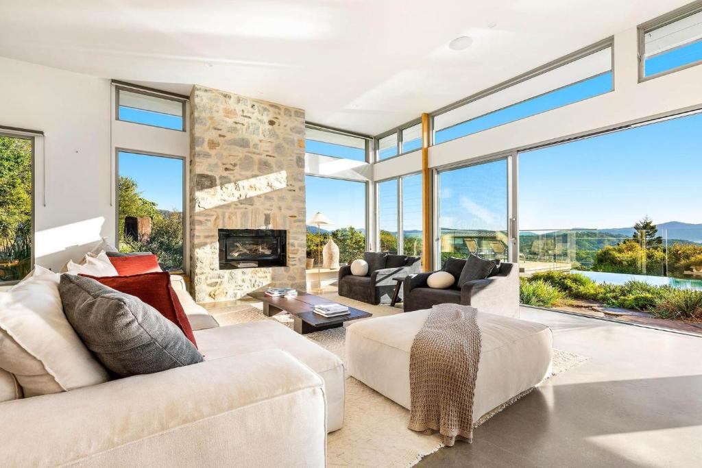 a living room with a fireplace and large windows at The Springs - architect-designed home with pool in Mullumbimby